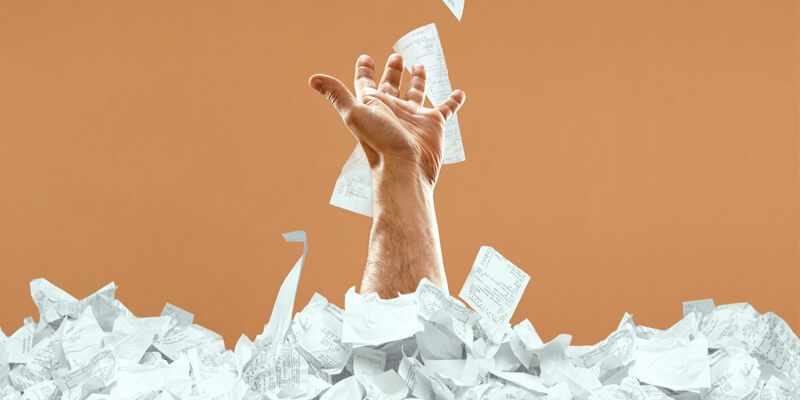 hand reaching out of a pile of paper receipts