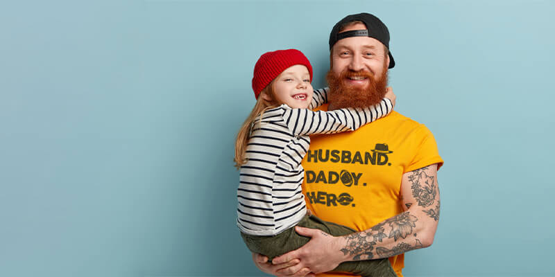 man with a ginger beard holding his daughter and wearing daddy t-shirt