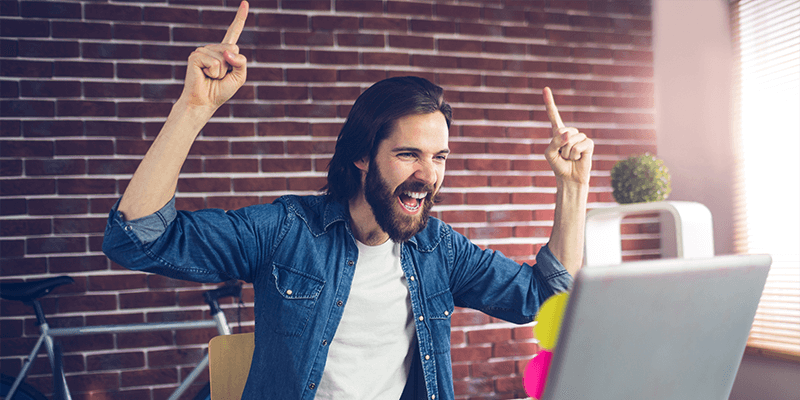 happy man working on a laptop pointing up in delight