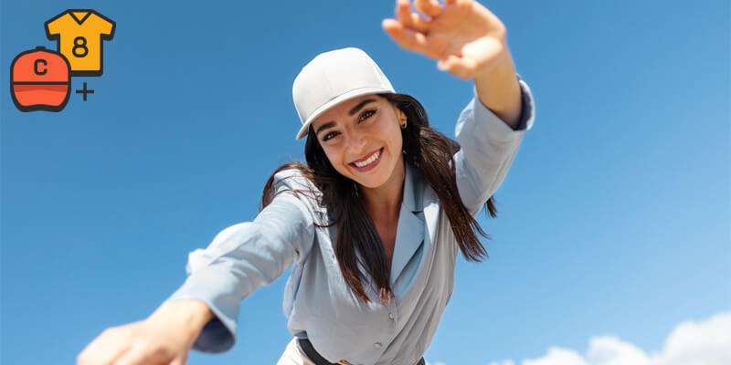 woman dancing outside in the sunshine wearing a white cap