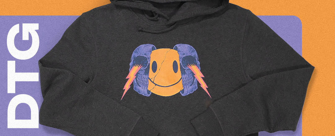 a grey hoodie with a centre print featuring a purple skull, a yellow smiley face and red lightning bolts