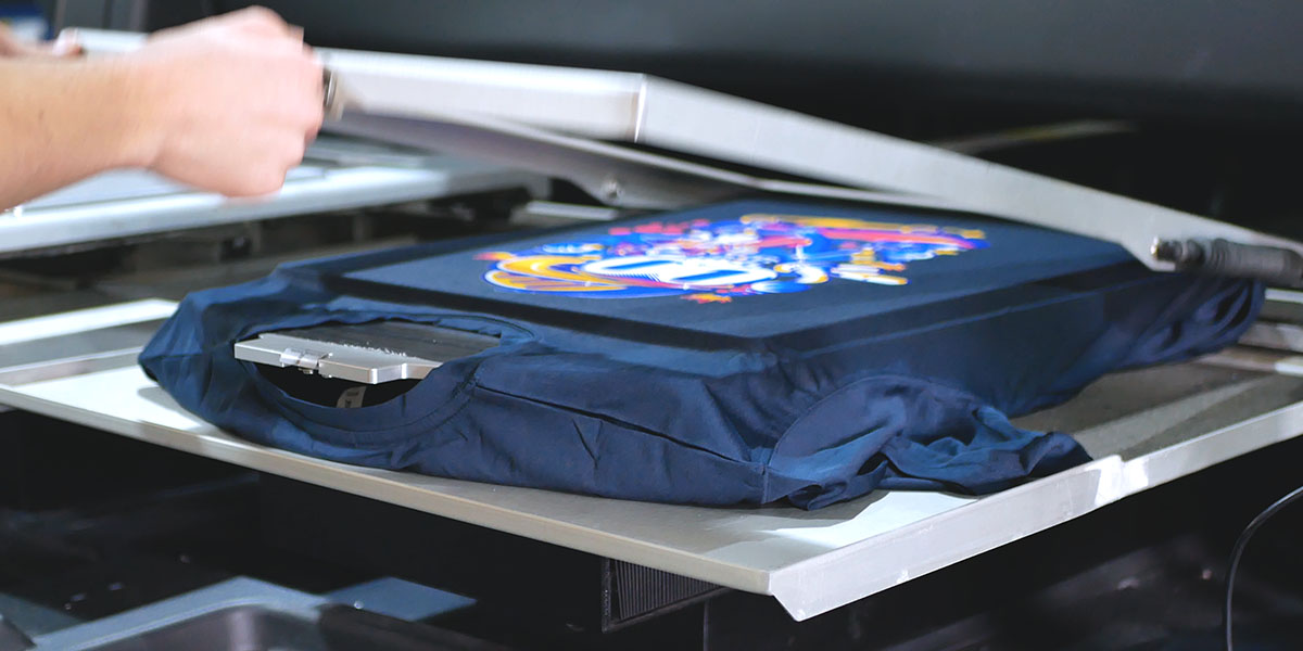 a printed t-shirt being taken off the dtg printer with a vibrant design