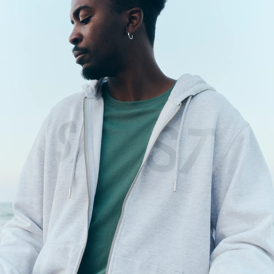 a closeup of the zip hoodie in cream heather grey showing the premium detailing