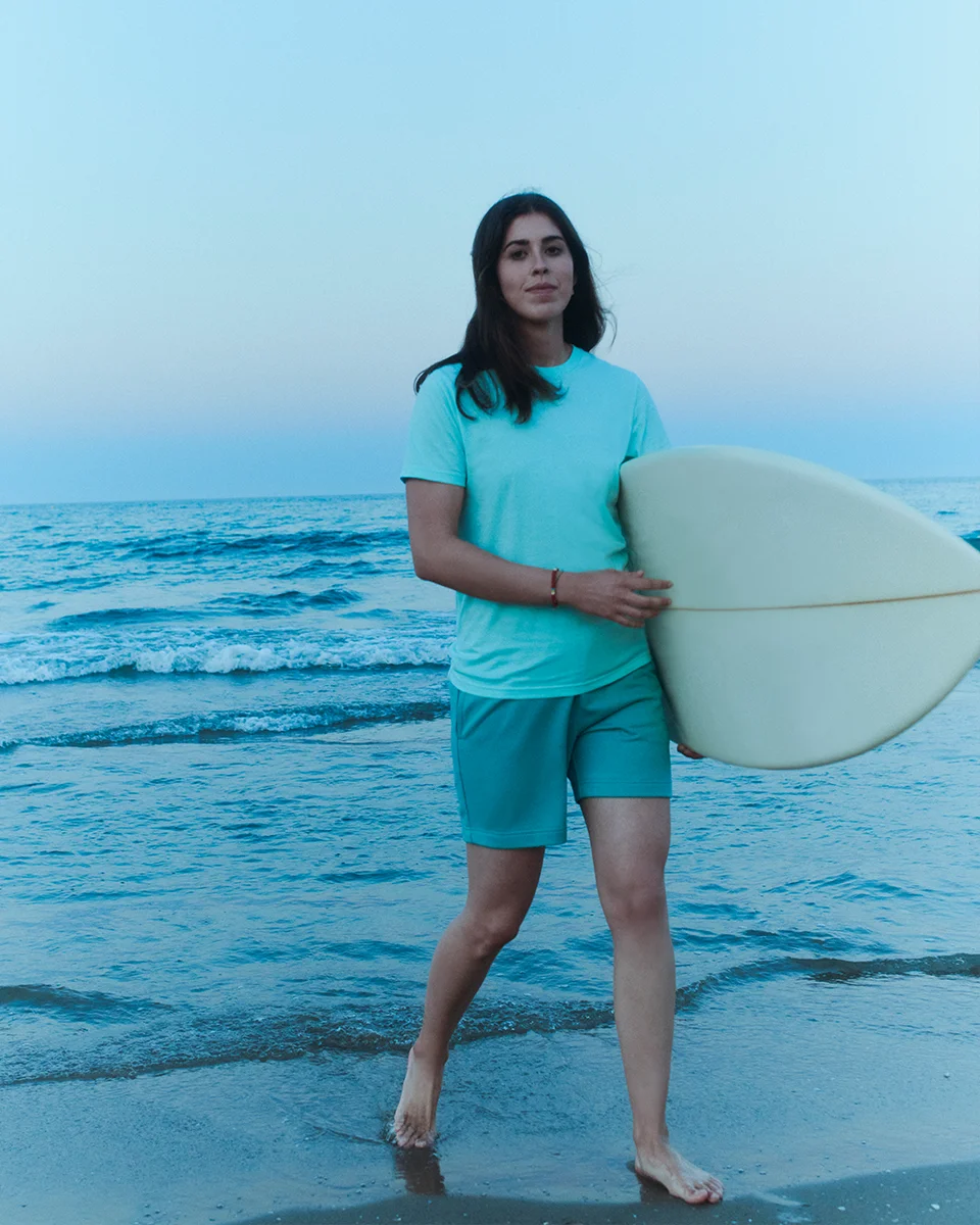 vintage style photo of a woman surfing in a blue t-shirt and blue shorts